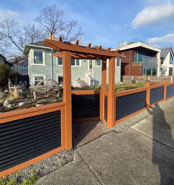 Custom cedar and corrugated metal fence with pergola-style gate in a front yard