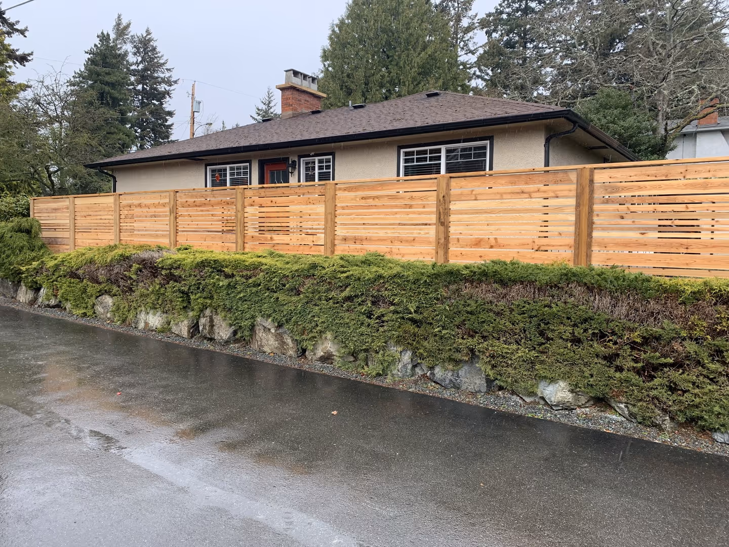 Single-story home with new horizontal cedar privacy fence on a rock retaining wall.