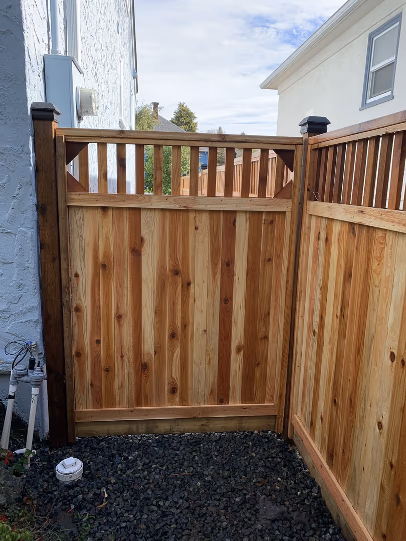 Wood privacy fence gate with slatted top in a side yard