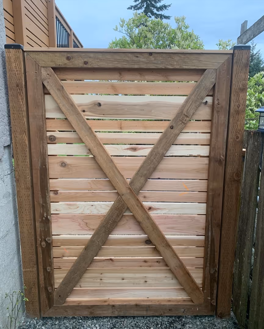 Wooden gate with horizontal slats and an X-brace between fence posts.